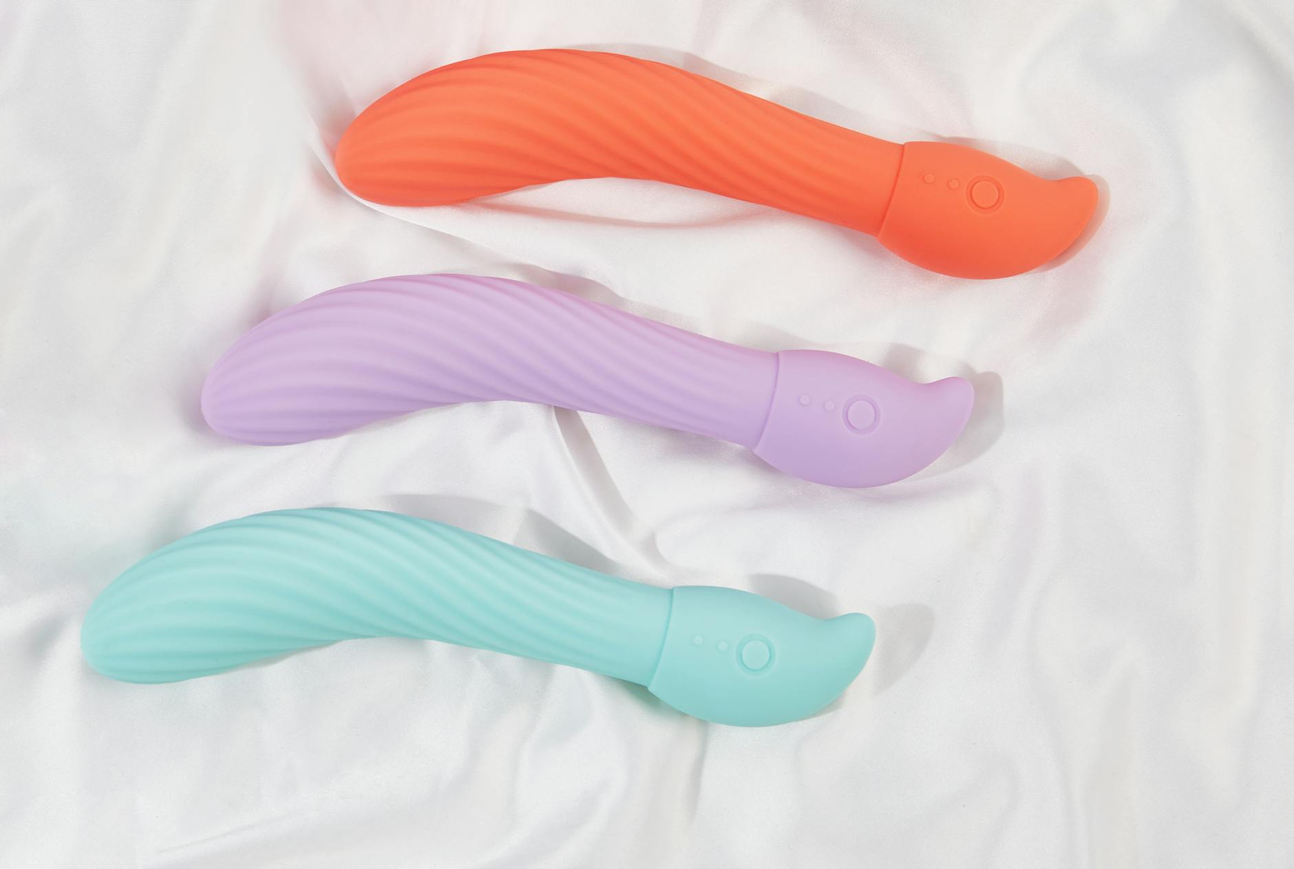 Hand holding an orange vibrator against a minimalistic purple backdrop, symbolizing modern sensuality and self-care