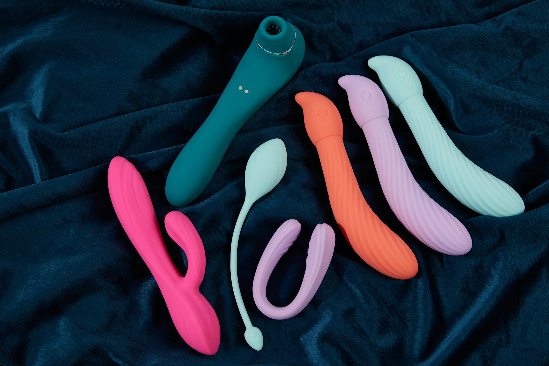Hand holding a blue clitoral vibrator against purple background, symbolizing self-care and emotional healing