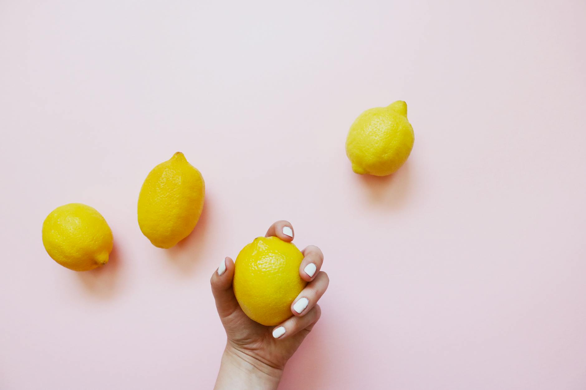 A hand holding a lemon on a soft pink background, symbolizing fresh approaches to sexual wellness and medication side effects
