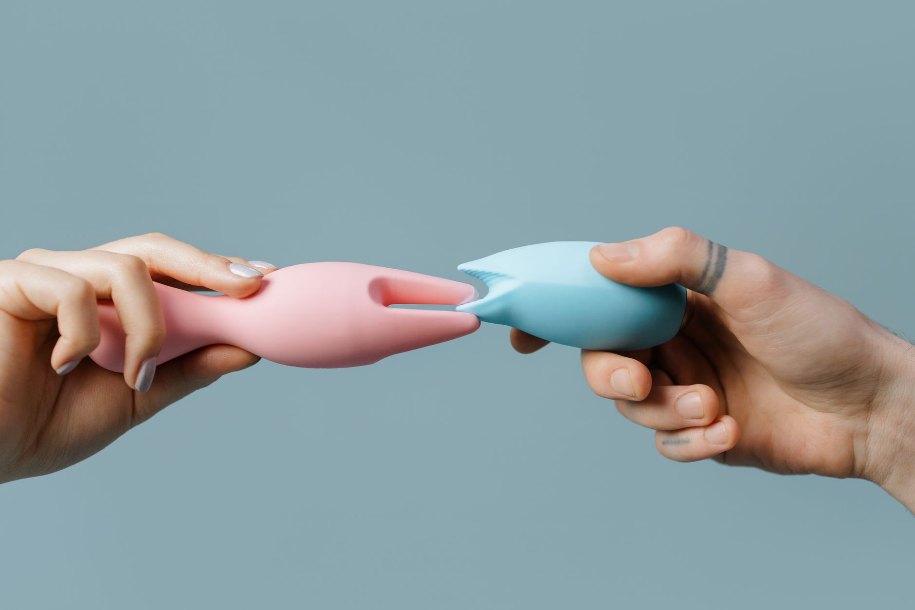 Hand holding a vibrator against a minimalist purple backdrop